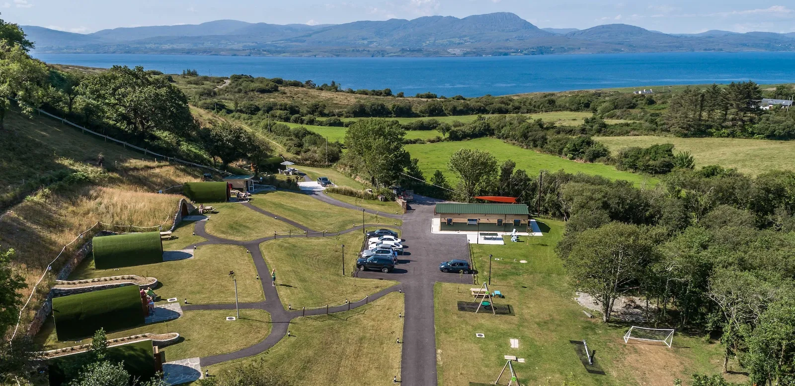 Aerial view of the green-roofed pods at Goats Path Pod Park above Bantry Bay